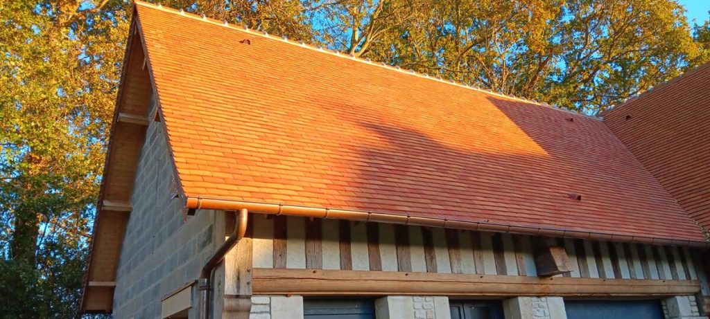 Toiture en tuile plate de pays et gouttière cuivre sur maison à colombages